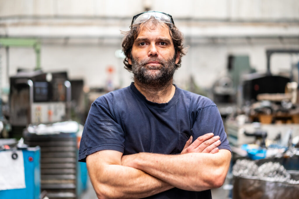 A lathe machine operator standing with arms crossed