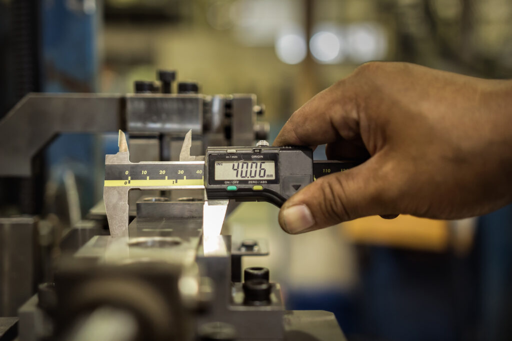 a machinist using calipers on a workpiece