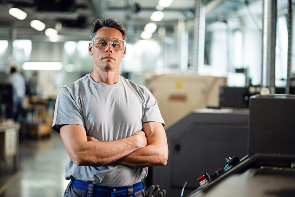 A milling machine operator standing with arms crossed